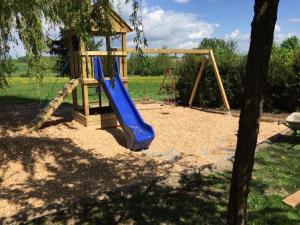 a playground with a blue slide and a tree at Landhaus Rössle in Schwäbisch Hall