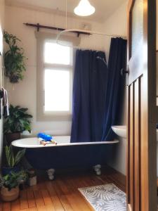 uma casa de banho com uma banheira azul e uma janela em 1920s Stay in Whanganui em Whanganui