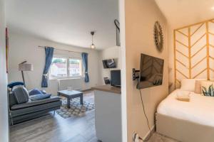 1 dormitorio con cama, sofá y TV en Chambre 26m - Salon et kitchenette privé - WIFI, en Woippy
