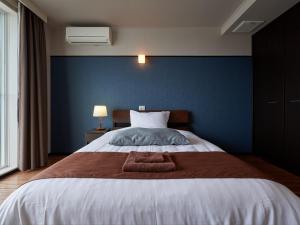 a bedroom with a large bed with a blue wall at Chateraise Lodge Atami in Atami