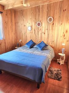 - une chambre avec un lit bleu et des murs en bois dans l'établissement Cabañas Entre copihues, à Osorno