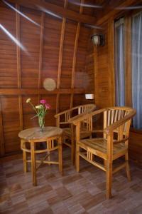 een kamer met 2 stoelen en een tafel met een vaas met bloemen bij The Peace Arta Bungalow in Nusa Penida