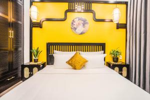 a bedroom with a white bed with a yellow wall at Lamy's House Cần Thơ in Can Tho