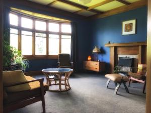 een woonkamer met blauwe muren en een tafel bij 1920s Stay in Whanganui in Whanganui