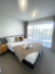 sypialnia z dużym łóżkiem i dużym oknem w obiekcie Alpine Junction Townhouse Apartments, Lodge & Hotel w mieście Wanaka