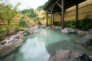 een groot zwembad met rotsen en een gebouw bij Wafu Ryokan Misato in Minamioguni
