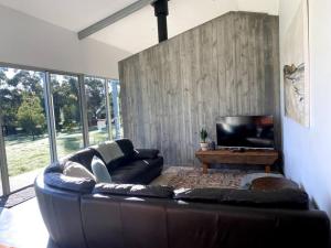 ein Wohnzimmer mit einem Ledersofa und einem TV in der Unterkunft Isle of Kilcarnup in Margaret River Town