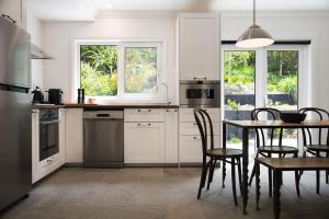 a kitchen with white cabinets and a table with chairs at Annecy House in Daylesford