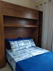 a bed with a wooden headboard and blue sheets and pillows at Loft Aconchegante no Centro de Niterói!! in Niterói