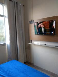 1 dormitorio con TV en la pared en Loft Aconchegante no Centro de Niterói!!, en Niterói