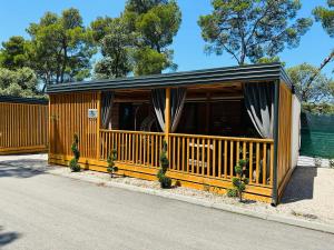 a wooden building with a porch with curtains at Pearl of the Biograd in Biograd na Moru