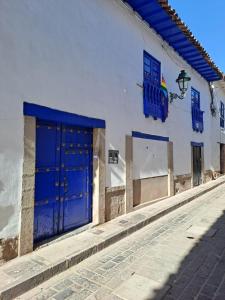 a white building with blue doors on a street at Marina's House Cusco Centro in Cusco