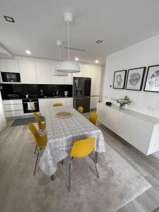 a kitchen and dining room with a table and yellow chairs at Modern 1 Bedroom City Center Aveiro Apartment in Aveiro