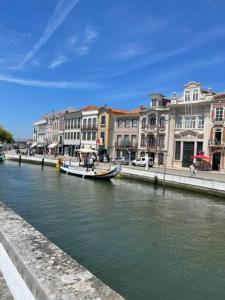 a boat on a river in a city with buildings at Modern 1 Bedroom City Center Aveiro Apartment in Aveiro