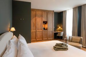 a bedroom with a white bed and a desk at Hotel des Brasseurs in De Haan +51 photos