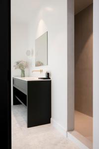 een badkamer met een zwart-witte wastafel en een spiegel bij Hotel des Brasseurs in De Haan