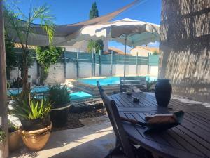 a wooden table and chairs next to a swimming pool at Maison de ana in Arles