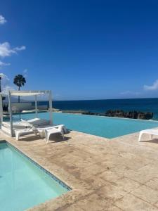 a swimming pool with chairs and the ocean in the background at DesSea Island-Sosua Ocean Village in Sosúa
