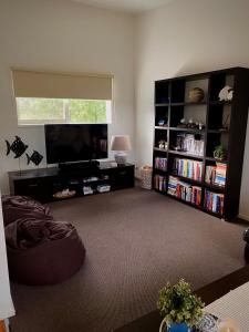 ein Wohnzimmer mit einem Flachbild-TV und einem Bücherregal in der Unterkunft Red Rocks Beach Retreat Free Wifi and Foxtel in Cowes