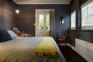 een slaapkamer met een groot bed en een gele deken bij Aysgarth in Daylesford
