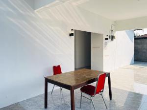 a dining room with a wooden table and two red chairs at RedDoorz Syariah @ Binjai Timur in Binjai