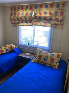 - une chambre avec 2 lits avec des draps bleus et une fenêtre dans l'établissement Villarrica: lago, volcán y parques naturales, à Villarrica