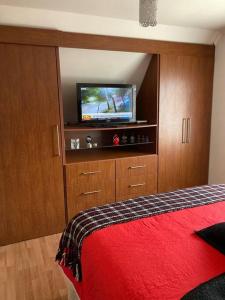 a bedroom with a bed and a television in a cabinet at Villarrica: lago, volcán y parques naturales in Villarrica