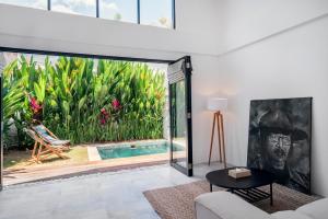 Una sala de estar con una gran puerta de vidrio que conduce a una piscina. en Umalas Living Villa, en Canggu