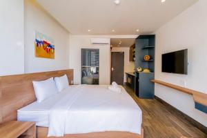a bedroom with a large white bed and a flat screen tv at Lantana House Boutique Da Nang by Haviland in Da Nang