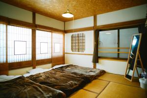 a bedroom with a bed in a room with windows at Hostel&Bar CAMOSIBA in Yokote