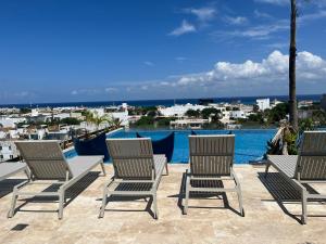 a group of chairs sitting on a patio overlooking the water at Menesse Midtown 2 206 y 209 in Playa del Carmen