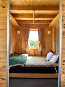 Una cama en una habitación de madera con ventana. en Margo's Garden Farmstay, Kiroro, en Akaigawa