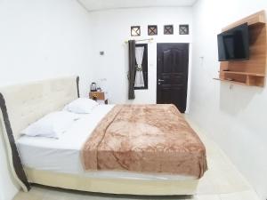 um quarto com uma cama com um cobertor castanho em Aipayung Homestay 