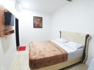 um pequeno quarto com uma cama e uma televisão em Aipayung Homestay 