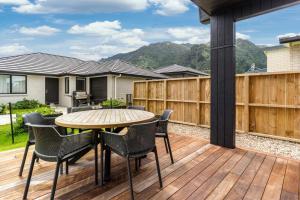 un patio con mesa y sillas en una terraza de madera en Custom designed holiday home, next to Cycleway., en Te Aroha