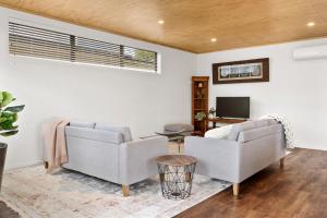 sala de estar con 2 sofás y TV en Custom designed holiday home, next to Cycleway., en Te Aroha