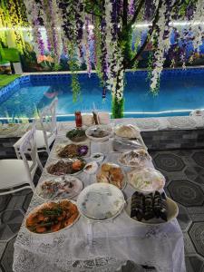 un tavolo con piatti di cibo accanto a una piscina di Tam Coc Mountain Flower Homestay a Vũ Lâm