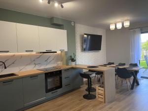 a kitchen with white cabinets and a table with chairs at Sosnówka Lake Apartament in Sosnówka