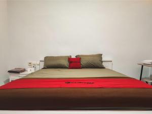 a bed with a red blanket on top of it at RedDoorz Syariah at Naffa Homestay in Sarolangun