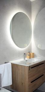 een badkamer met een wastafel en een ronde spiegel bij Vega del Tajo- CON PARKING GRATIS in Toledo