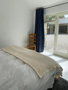 a bedroom with a bed and a chair and a window at Cornish Billys Barn in Penzance