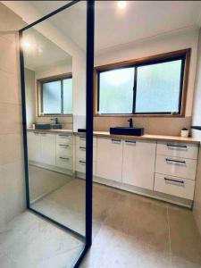 La salle de bains est pourvue d'un miroir, de lavabos et de fenêtres. dans l'établissement Rhyll Home with a View, à Rhyll