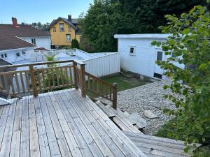 a wooden deck with a fence and a house at Nice apartment close to the sea with parking and garden in Arendal