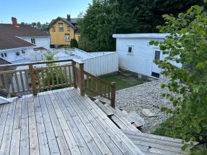 a wooden deck with a fence and a house at Nice apartment close to the sea with parking and garden in Arendal +43 photos