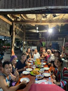 un grupo de personas sentadas alrededor de una mesa comiendo comida en Lazy Mango Home Stay, en Phumĭ Poŭthĭ Mâ Srei