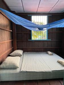two beds in a room with a mosquito net at Lazy Mango Home Stay in Phumĭ Poŭthĭ Mâ Srei