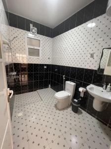 uma casa de banho em preto e branco com WC e lavatório em old muscat em Mascate