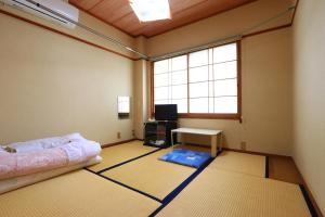 a room with a bed and a desk and a window at Suikoen in Yonago
