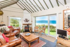 a living room with a couch and a table at Sheldrake, Spacious Villa, Panoramic Sea-views, Large Garden, By Beach in Sennen