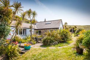 a house with palm trees and plants in front of it at Sheldrake, Spacious Villa, Panoramic Sea-views, Large Garden, By Beach in Sennen